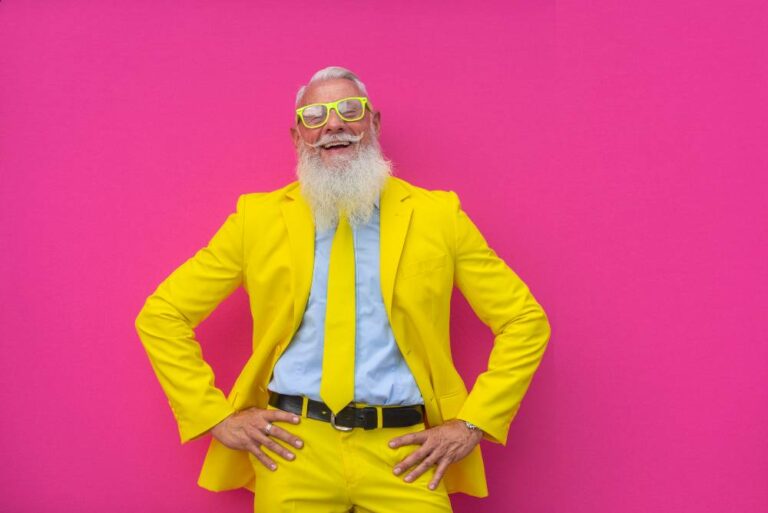 homme âgé avec barbe blanche, costume jaune sur fond fushia