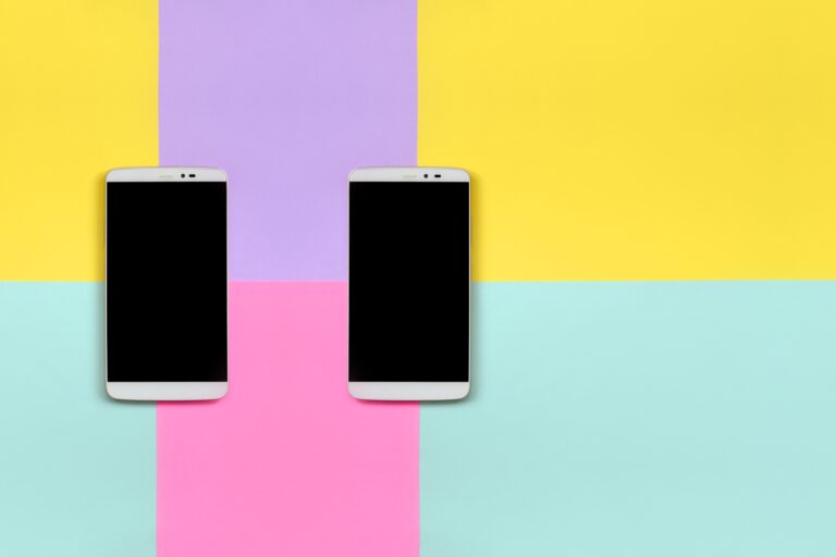 deux smartphones éteints sur fond jaune et violet
